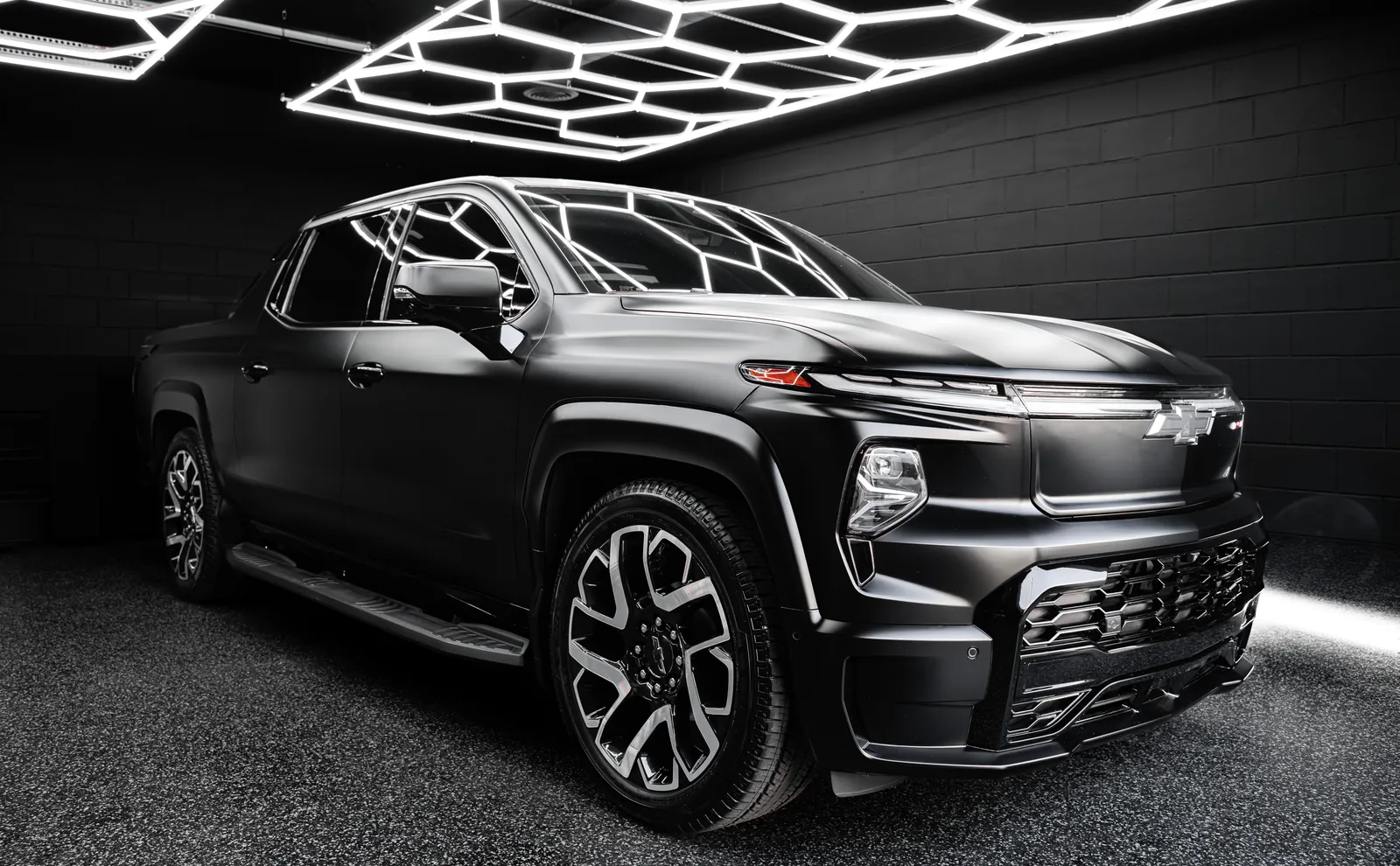 Satin black Chevrolet Silverado EV RST with full body Stealth paint protection film, front three-quarter view in the shop bay