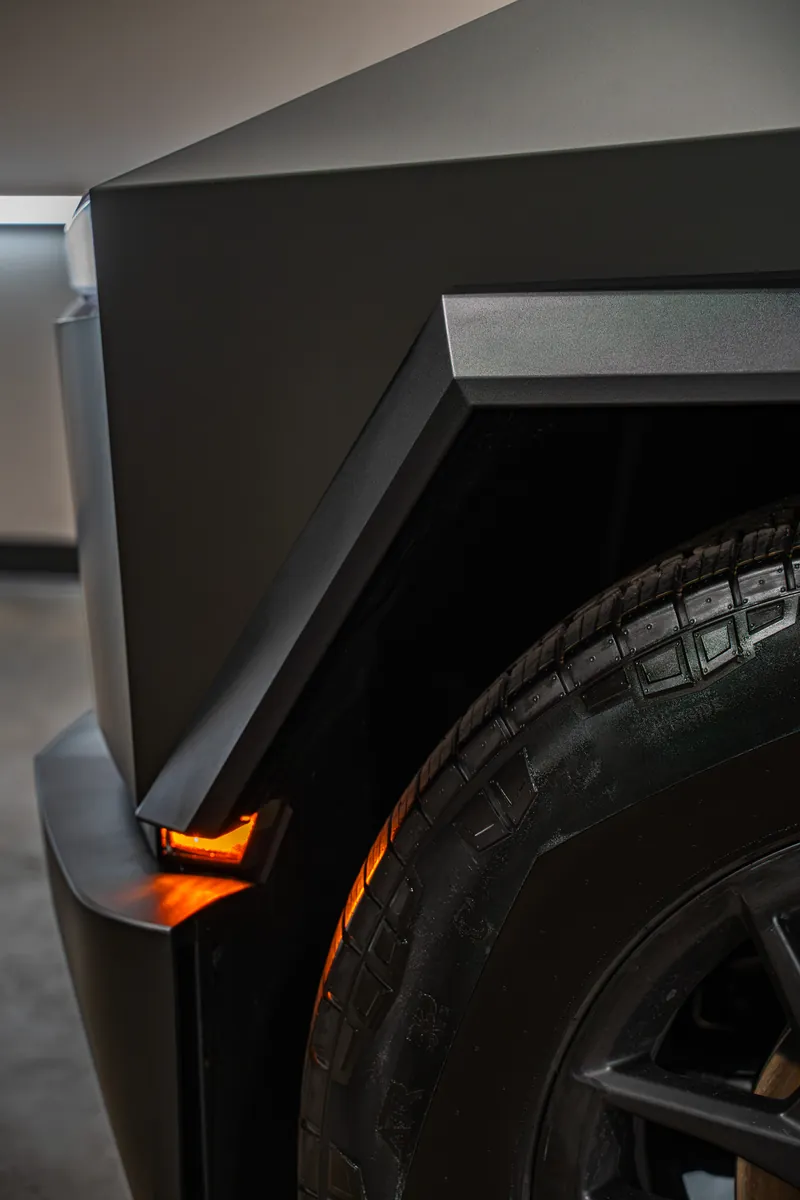 Fender flare and front tire of a grey-olive Tesla Cybertruck