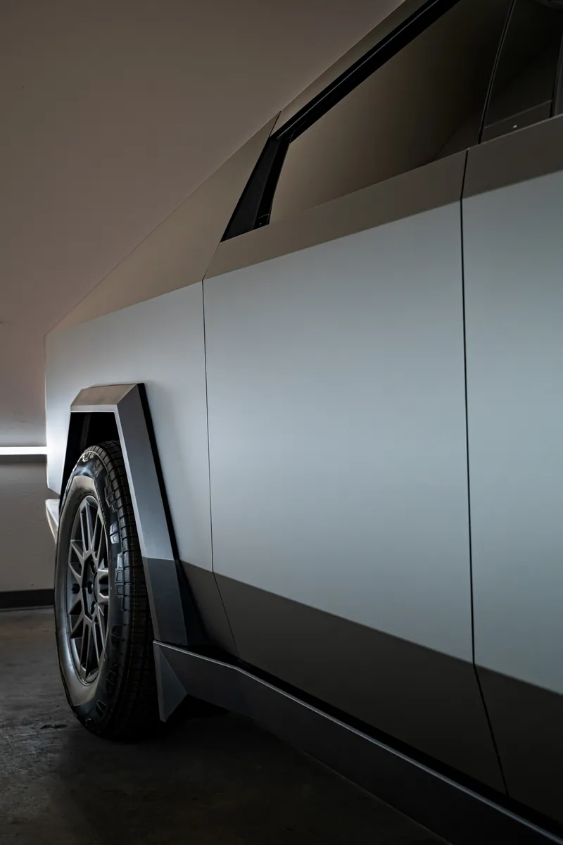 Side panels and front wheel of a grey-olive Tesla Cybertruck