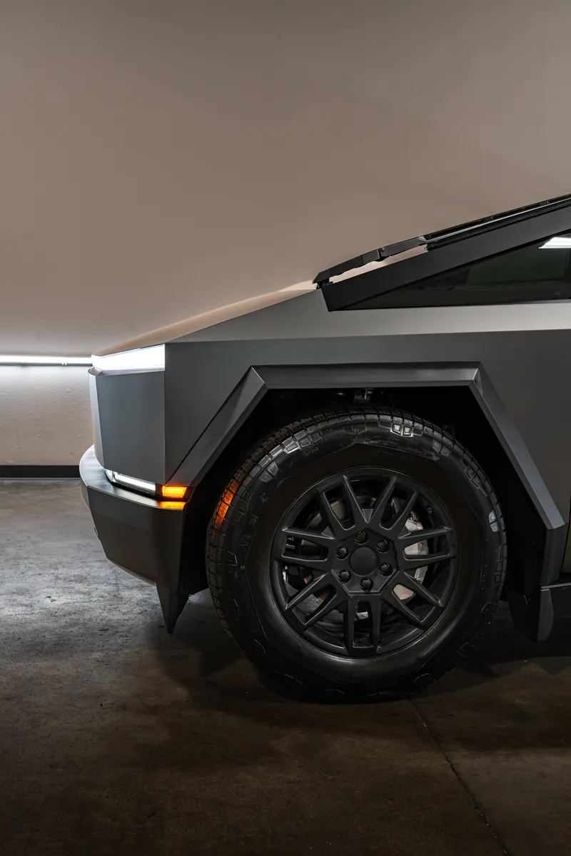 Front wheel and fender flare of a grey-olive Tesla Cybertruck
