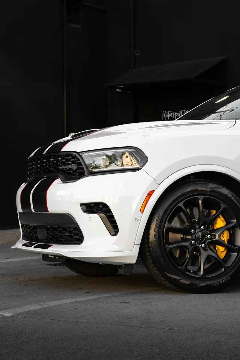 Front quarter of a white Dodge Durango SRT showing the grille, headlight and black wheel with yellow caliper
