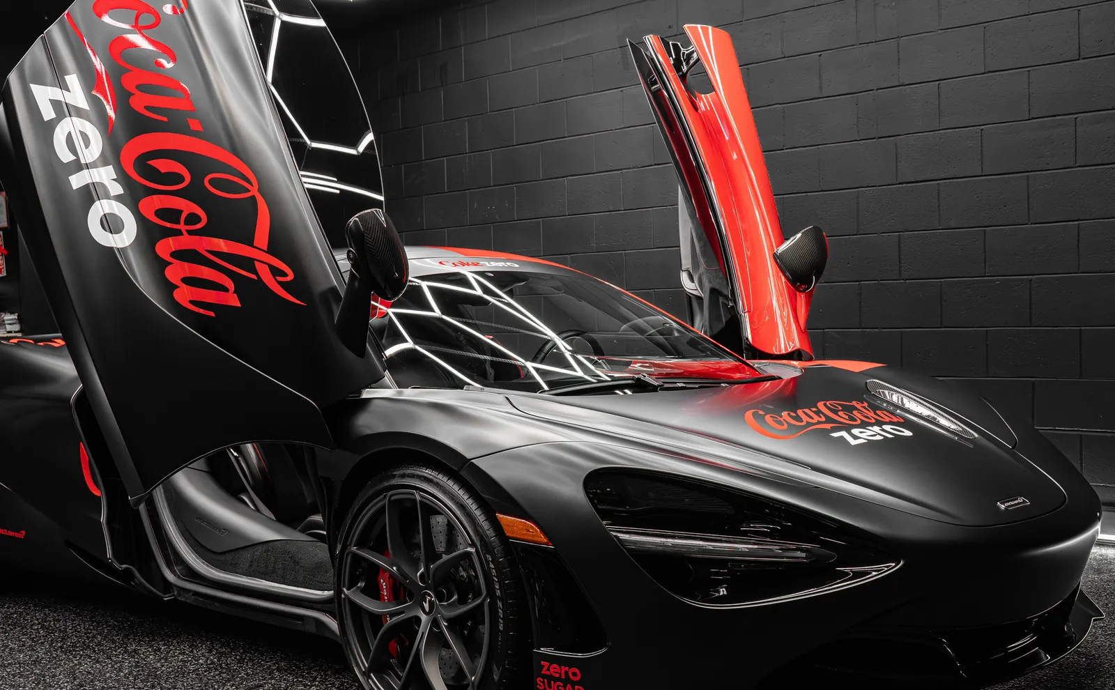 McLaren 720S with a red and black two-tone custom livery vinyl wrap and Coke Zero graphics, doors raised