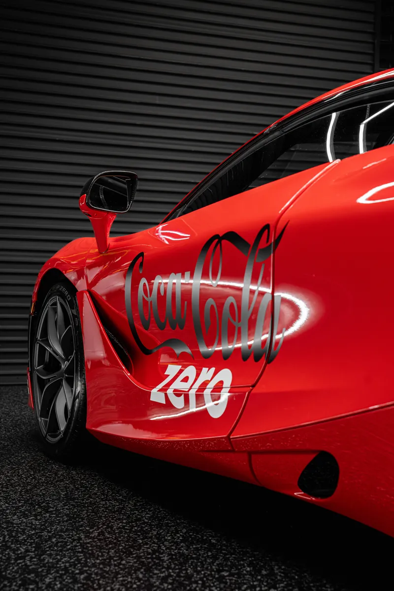 Side of a McLaren 720S with a red custom livery wrap and large Coke Zero logo