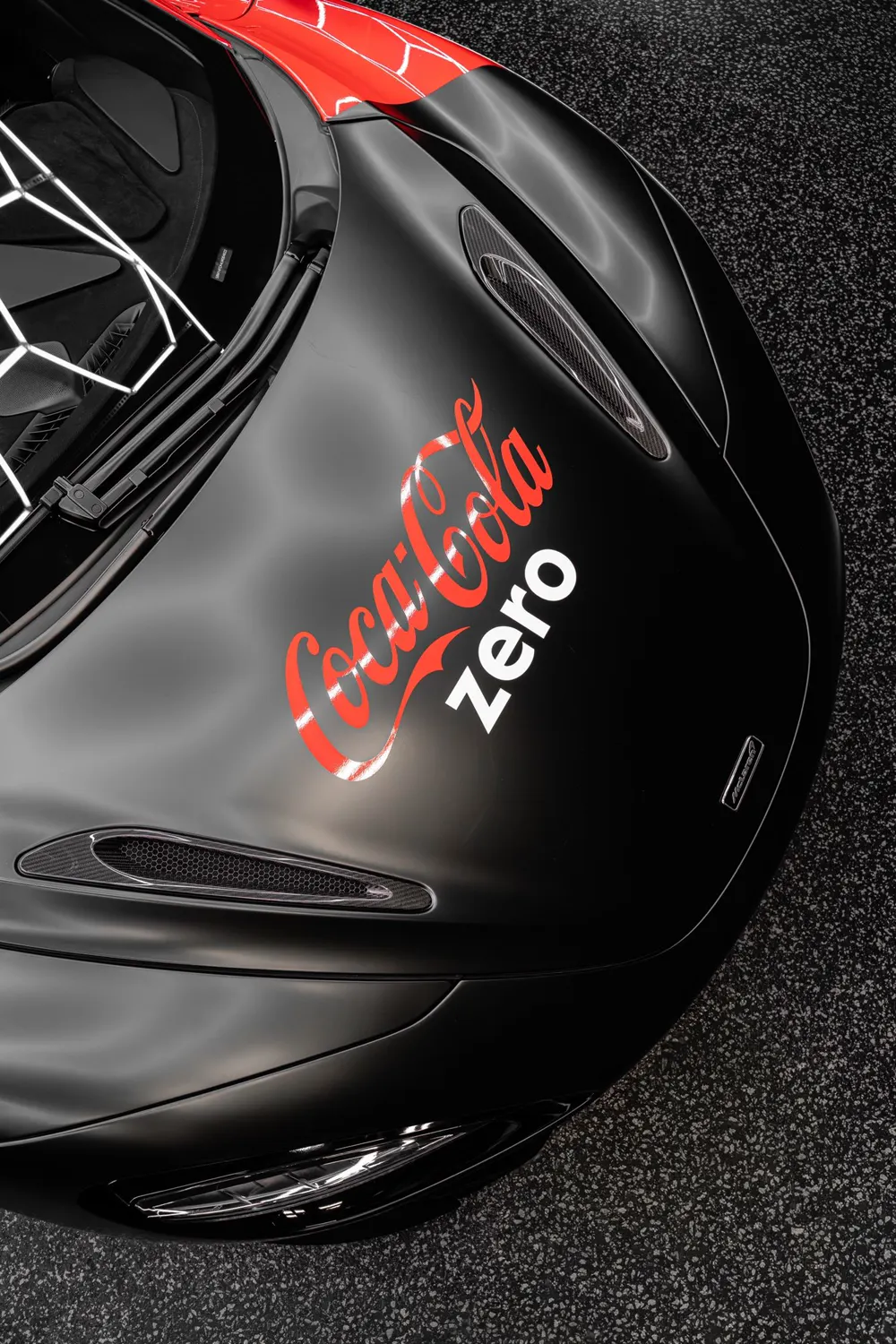 Overhead view of a satin black McLaren hood with livery graphics