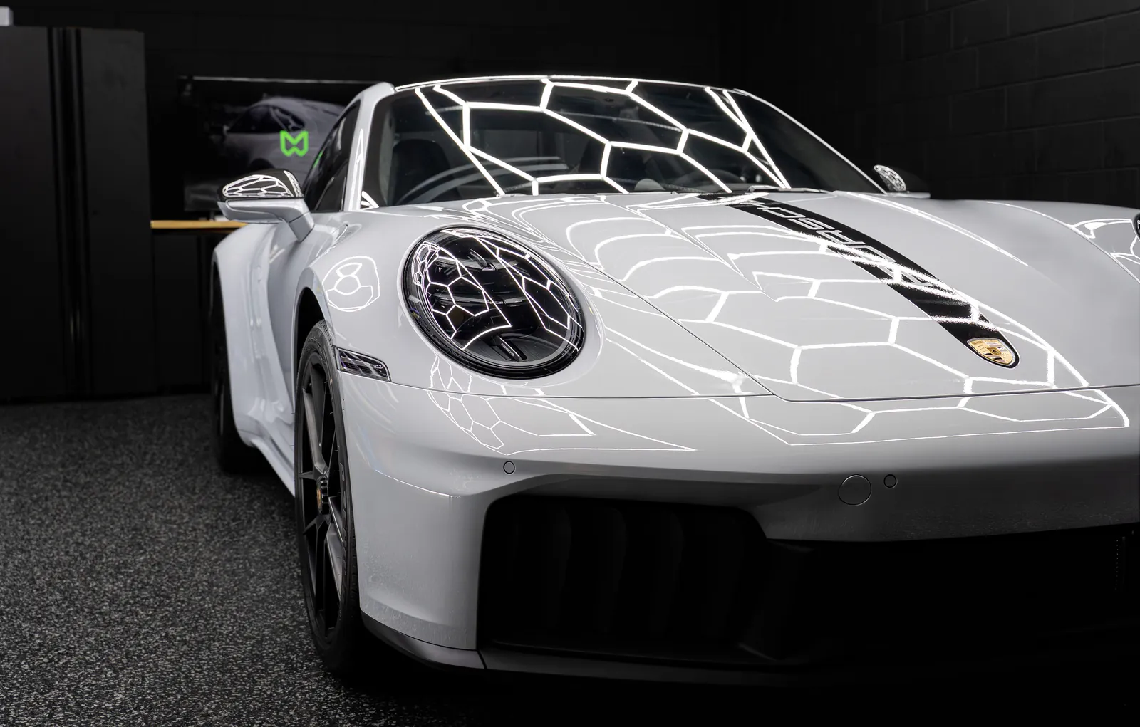 Headlight and front corner of a light grey Porsche 911 Carrera GTS