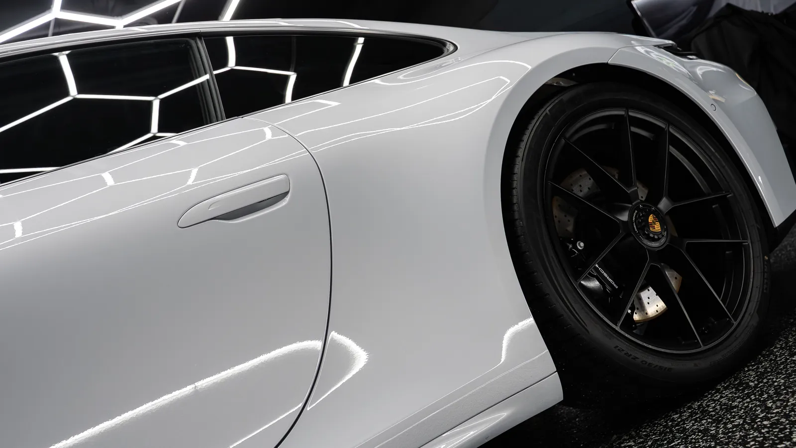 Door and rear wheel of a light grey Porsche 911 Carrera GTS