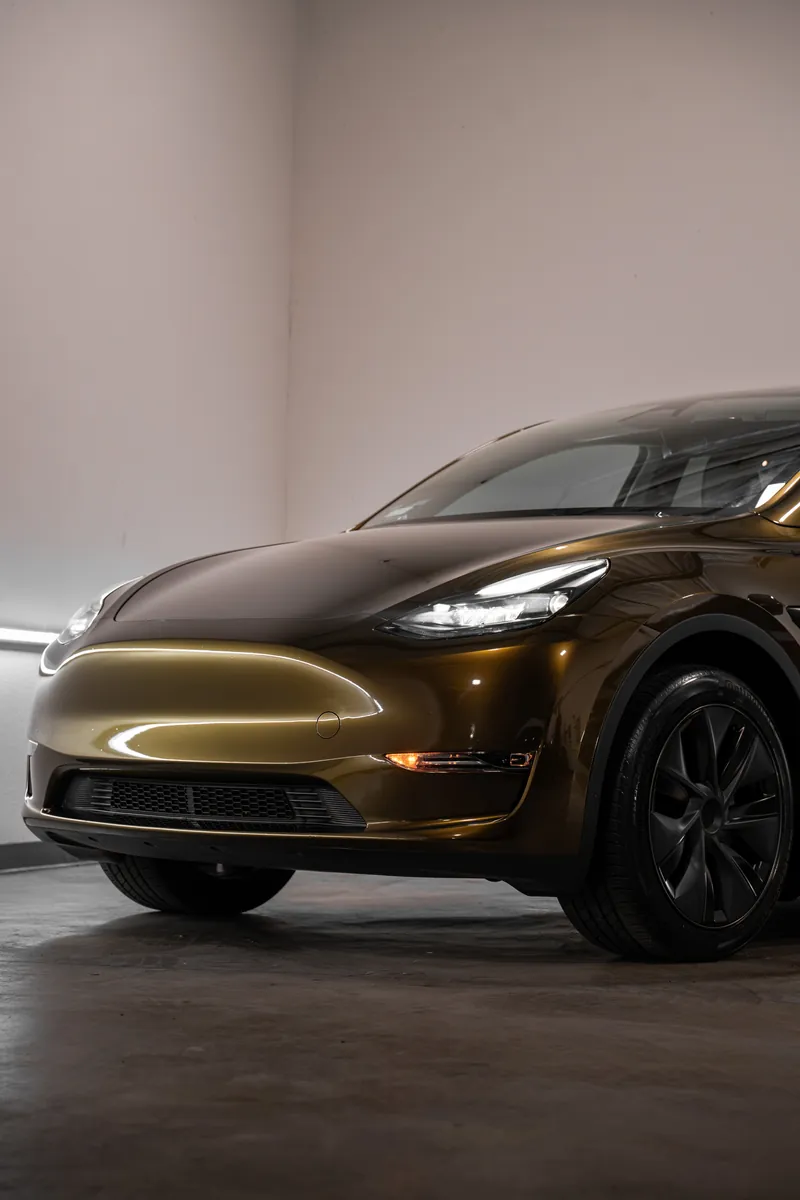 Front quarter of a bronze Tesla Model Y with a color change vinyl wrap