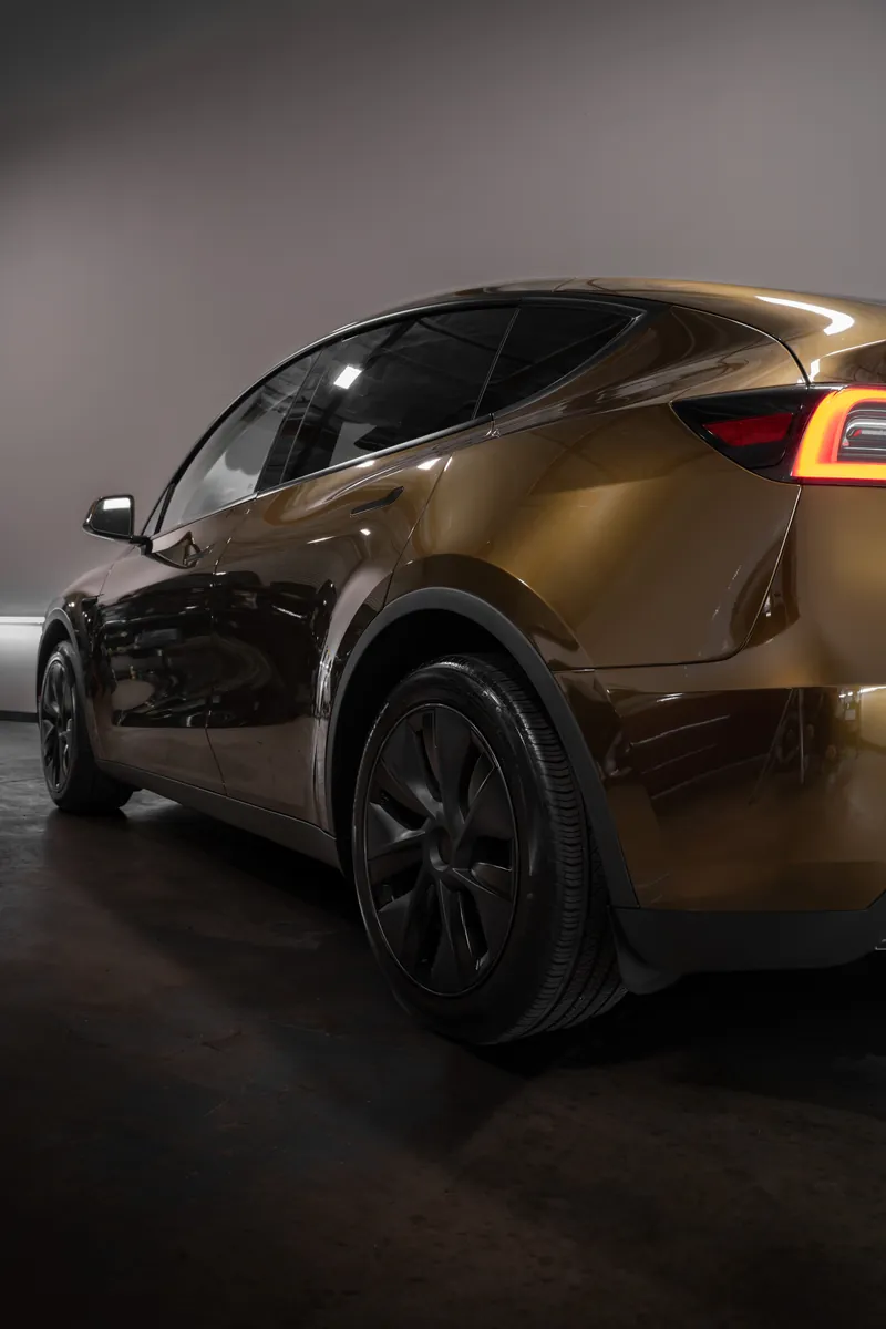 Rear three-quarter of a bronze Tesla Model Y with a color change vinyl wrap